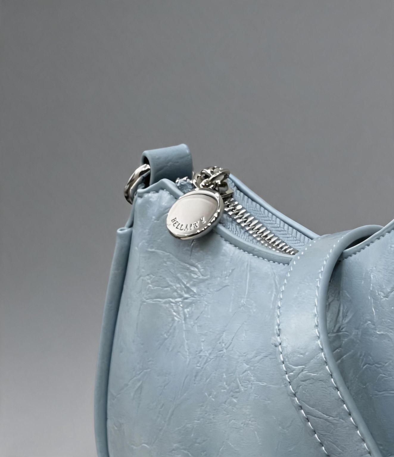 Close-up of the round zipper pull and textured light blue vegan leather