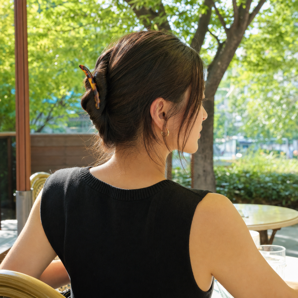 Relaxed low French twist secured with a tortoiseshell French hair pin at a sunny cafe terrace